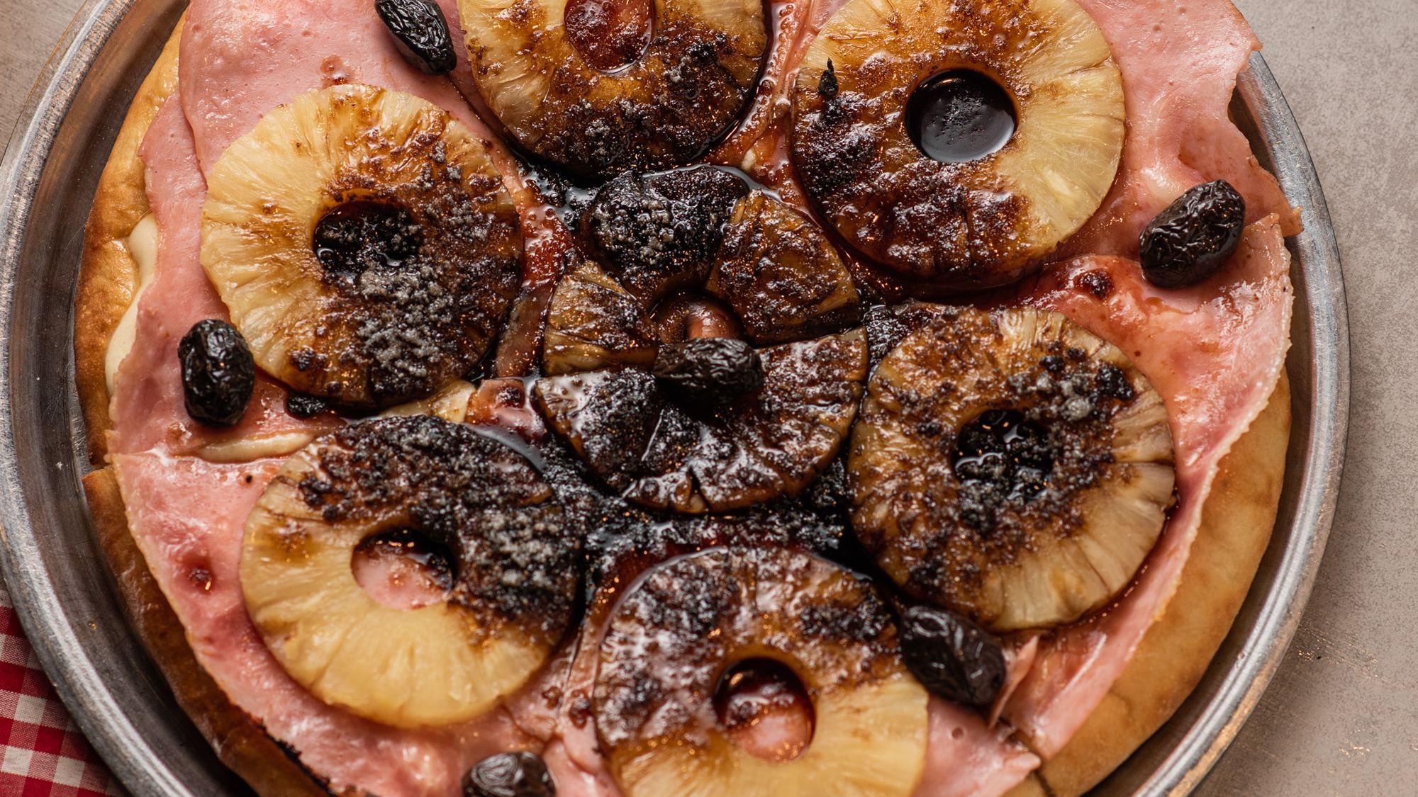 Pizza Abuelo Yuyi con jamón, ananá y aceitunas negras